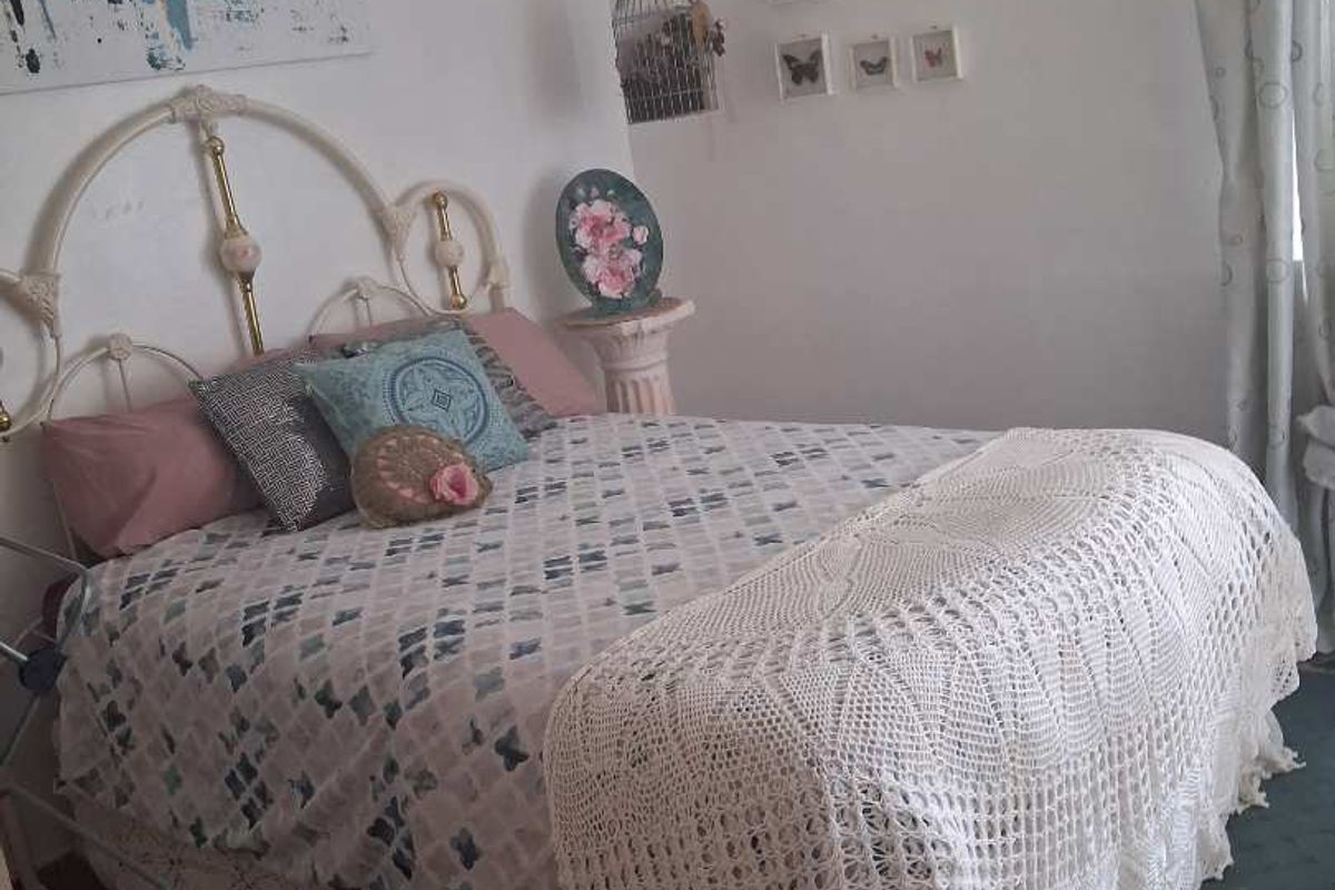 A bedroom featuring tiled flooring and a classic metal bed frame, offering a cozy and functional living space.