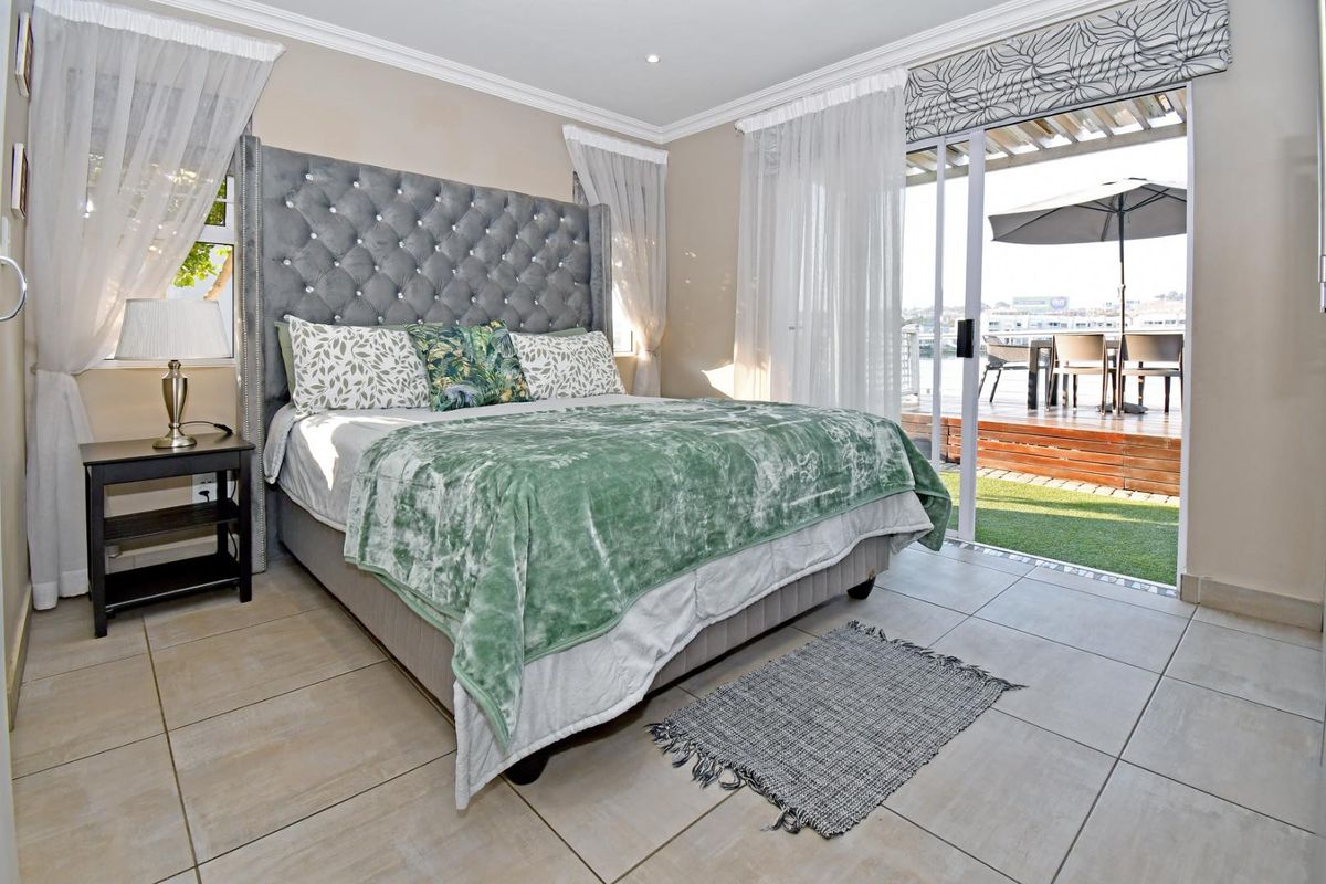 Spacious bedroom featuring tiled flooring, crown molding, and large sliding glass doors providing direct access to an outdoor patio area.