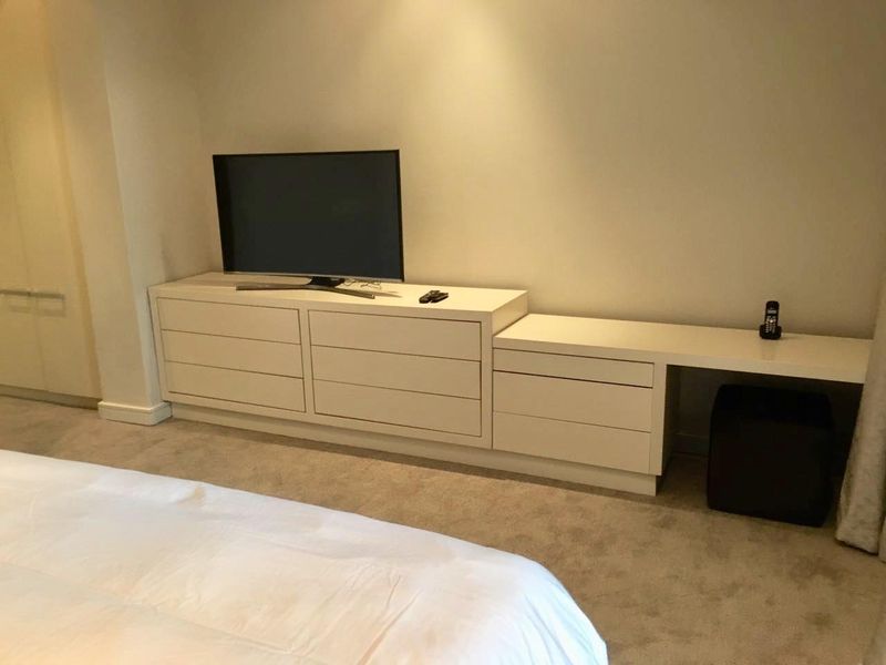 A bedroom featuring neutral carpet flooring, recessed lighting, and integrated built-in cabinetry with a matching desk area.