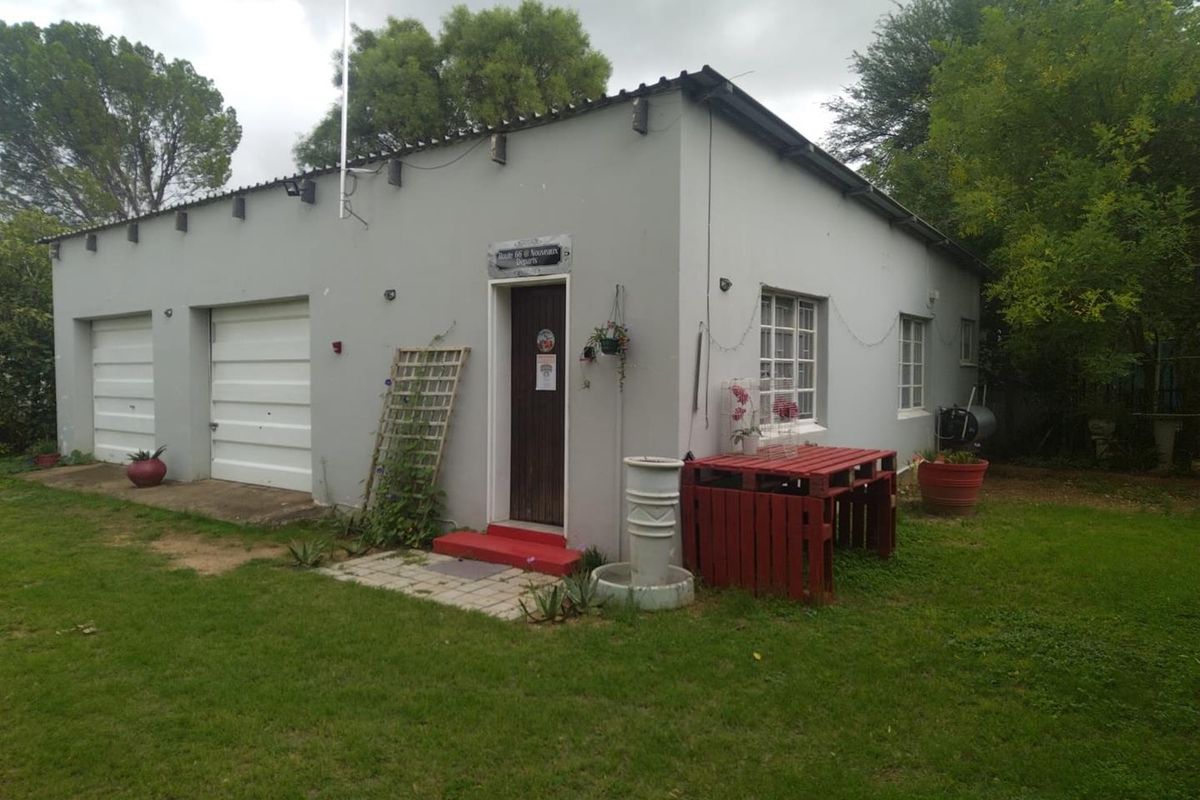 Rear view of a detached garage structure featuring two garage doors, a side entrance, and surrounding garden space.