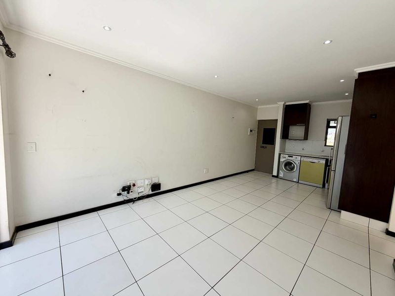 Open plan living area featuring tiled flooring, recessed lighting, and a compact kitchen space with integrated laundry connections.