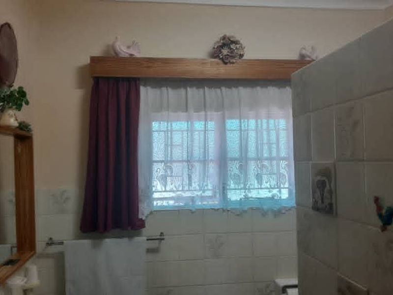 A bathroom featuring tiled walls, a window with a wooden pelmet, and a towel rail.