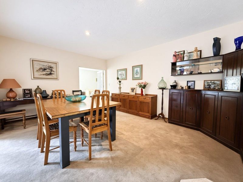 A spacious dining room featuring neutral wall finishes, carpeted flooring, and recessed downlighting, providing a functional area for family meals and entertaining.