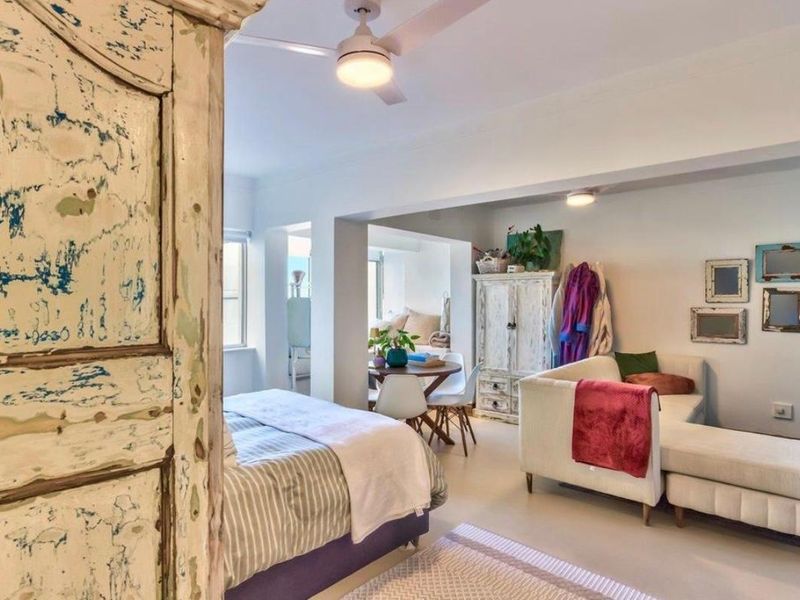 An open-plan living and bedroom area featuring neutral walls, ceiling fan, and recessed lighting, offering a versatile layout for comfortable apartment living.
