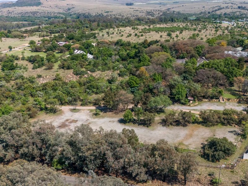 Aerial view of a large agricultural land parcel featuring mature trees, cleared open space, and established perimeter fencing in a rural setting.