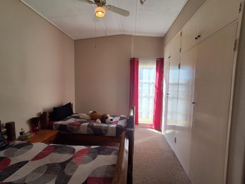 A bedroom featuring built-in cupboards, a ceiling fan, and carpeted flooring, requiring some cosmetic updates to improve its overall condition.
