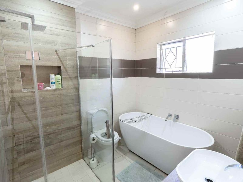 Modern bathroom featuring a freestanding bathtub, a glass-enclosed walk-in shower with a rain shower head, and a contemporary vessel sink.