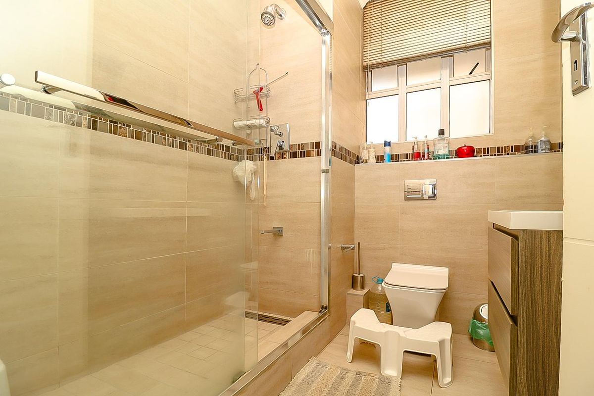 Modern bathroom featuring a glass-enclosed shower, wall-mounted toilet, and a sleek vanity cabinet with neutral tiled finishes.