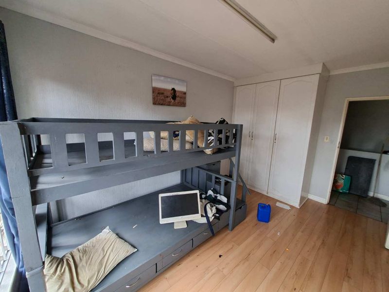 A bedroom featuring laminate flooring and built-in cupboards, requiring cosmetic updates to improve its overall condition and appeal.