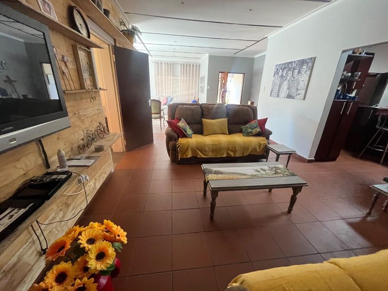 A living room featuring tiled flooring, recessed ceiling lighting, and a timber-clad feature wall, providing a functional and lived-in space.