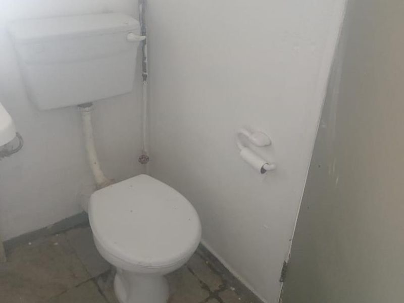 A functional bathroom space featuring a standard toilet and tiled flooring, currently in need of cosmetic updates and maintenance.