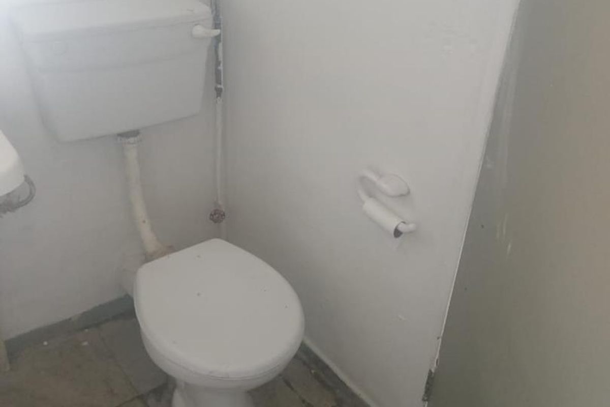 A functional bathroom space featuring a standard toilet and tiled flooring, currently in need of cosmetic updates and maintenance.