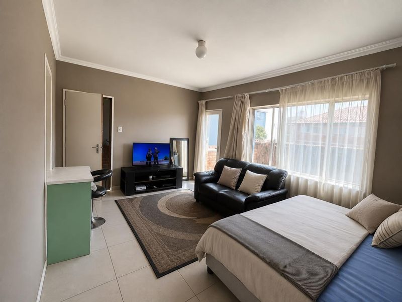 Open-plan living and sleeping area featuring tiled flooring, large windows with natural light, and a built-in breakfast counter.