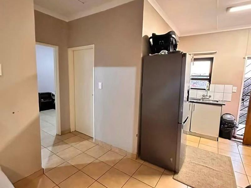 Open plan living area featuring tiled flooring and a compact kitchen corner with built-in cabinetry and sink.