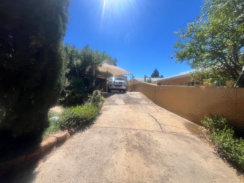 Front view of the property featuring a concrete driveway, boundary wall, and a retractable awning over the entrance area.