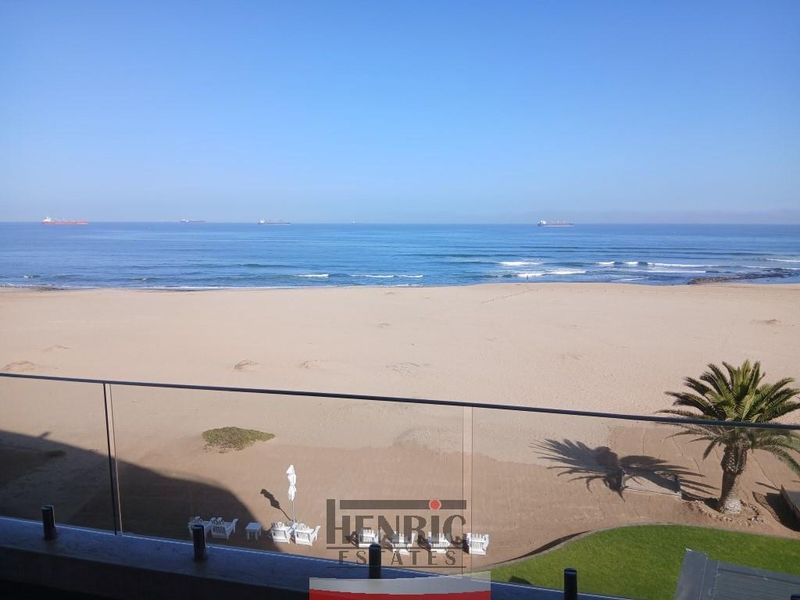 Stunning panoramic ocean and beach view from a private balcony featuring a modern glass balustrade.