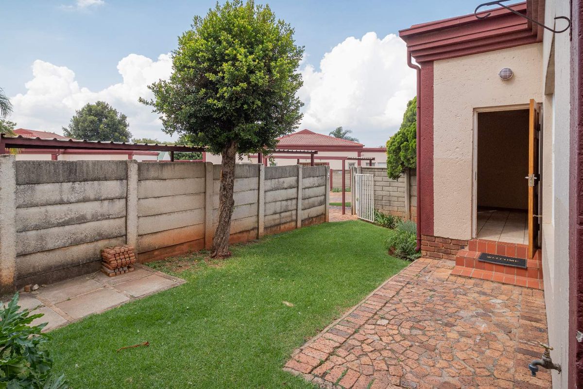 A private rear garden featuring a paved patio area, a well-maintained lawn, and a secure precast concrete boundary wall.
