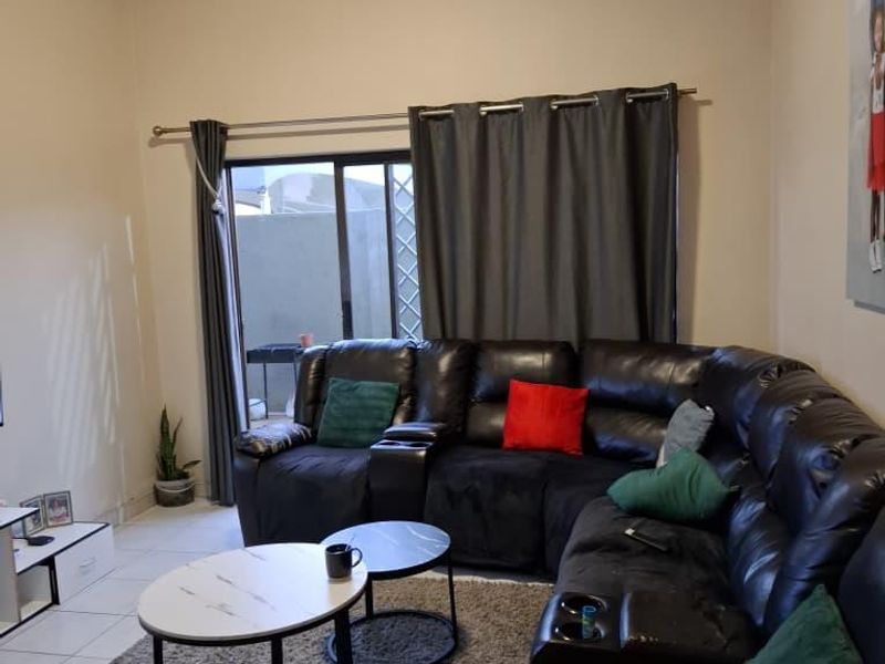 A comfortable living room featuring tiled flooring and a large sliding glass door that provides access to the outdoor area.