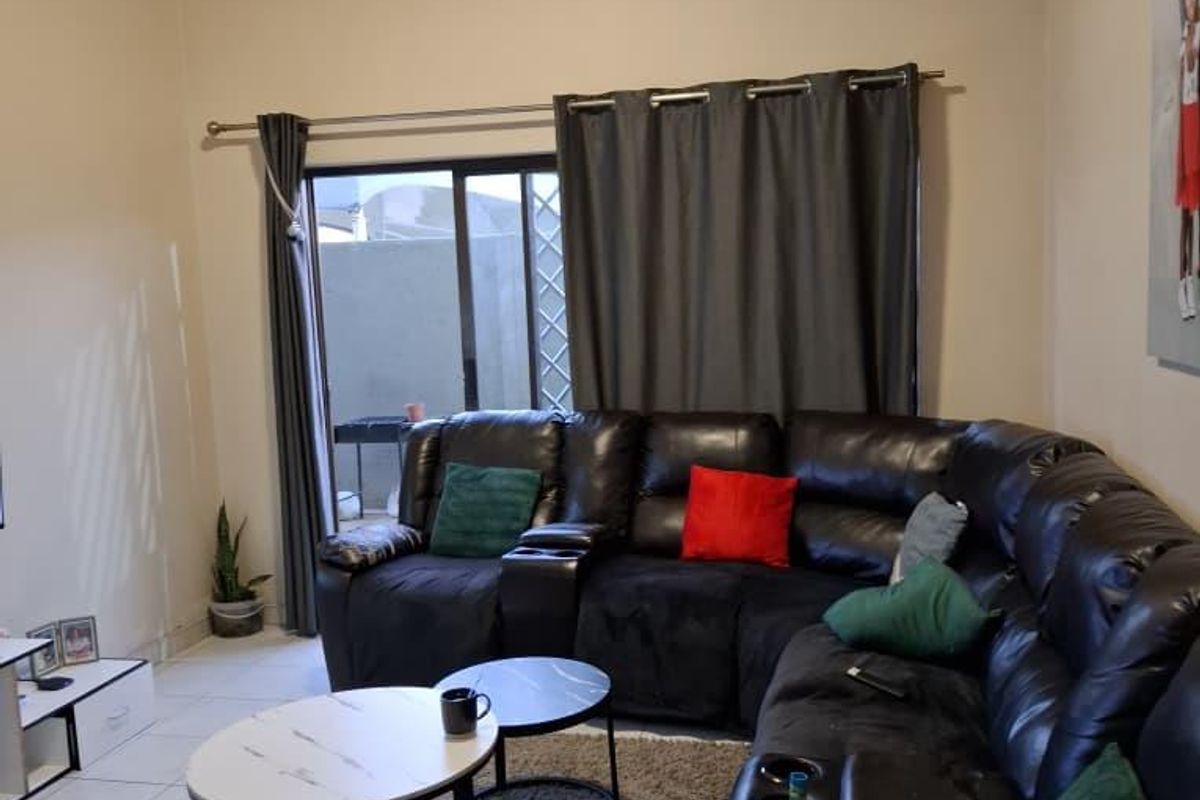 A comfortable living room featuring tiled flooring and a large sliding glass door that provides access to the outdoor area.
