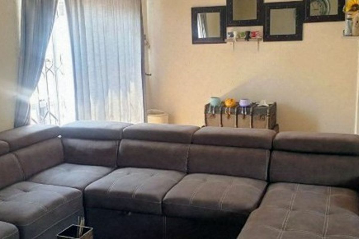 A living room area featuring a sliding door with an integrated security gate, providing access to the exterior.