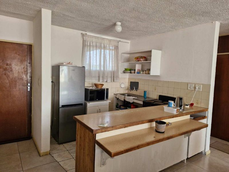 A functional kitchen featuring a breakfast bar, tiled backsplash, and basic cabinetry, offering potential for modernization and aesthetic updates.