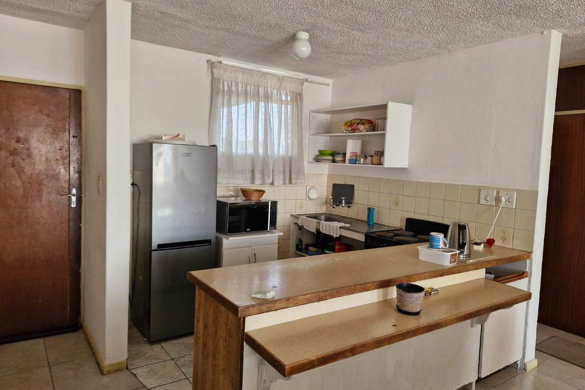 A functional kitchen featuring a breakfast bar, tiled backsplash, and basic cabinetry, offering potential for modernization and aesthetic updates.