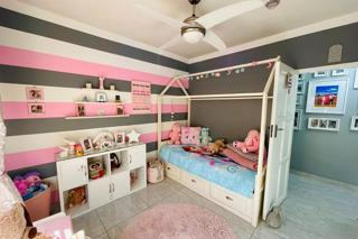 A bedroom featuring tiled flooring, a ceiling fan, and built-in shelving, currently decorated with a striped wall finish.