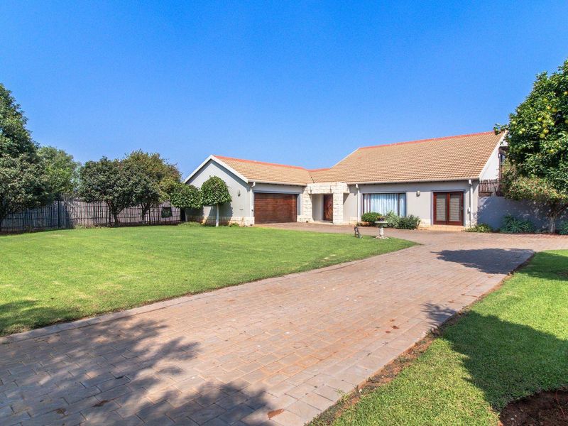 A well-maintained single-story family home featuring a paved driveway, double garage, stone-clad entrance, and a spacious front lawn.