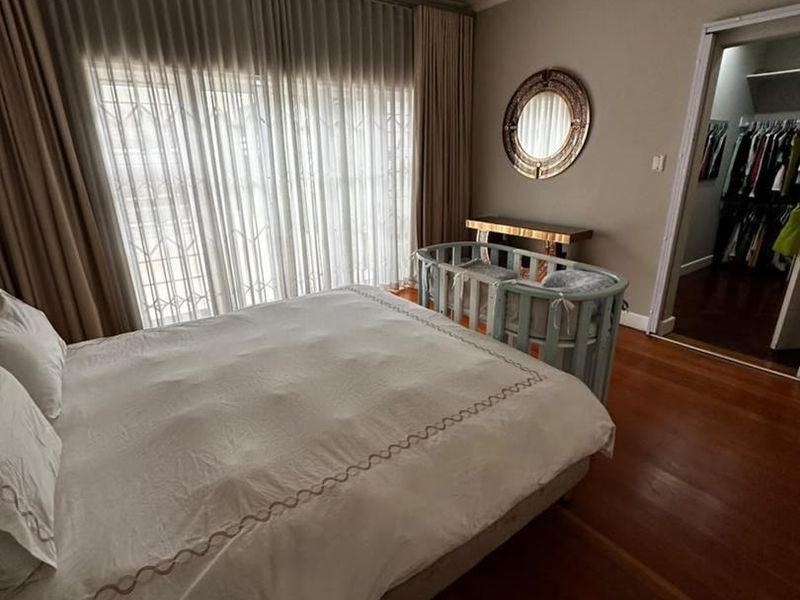 Spacious bedroom featuring hardwood flooring, recessed lighting, and a convenient walk-in closet, with direct access to the outdoors through a sliding glass door.