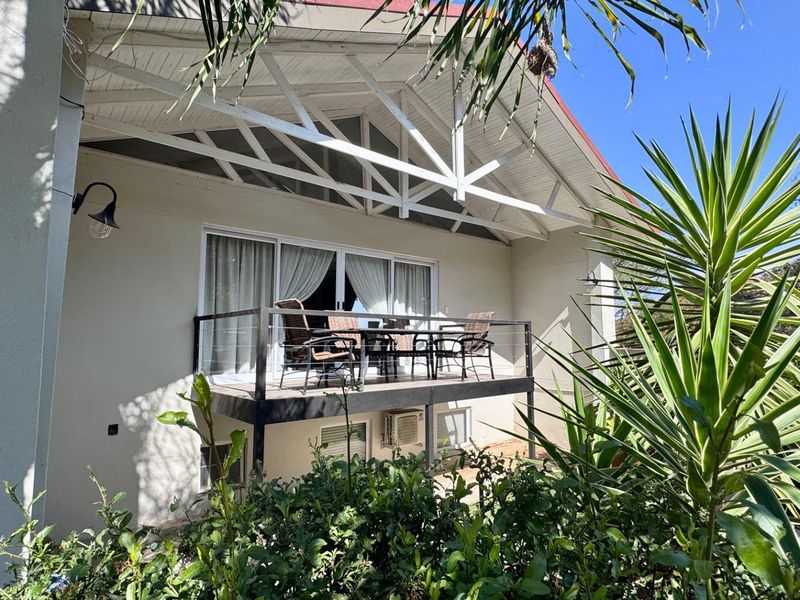 A covered patio area featuring a raised deck with metal railings, accessible via sliding glass doors from the main house structure.