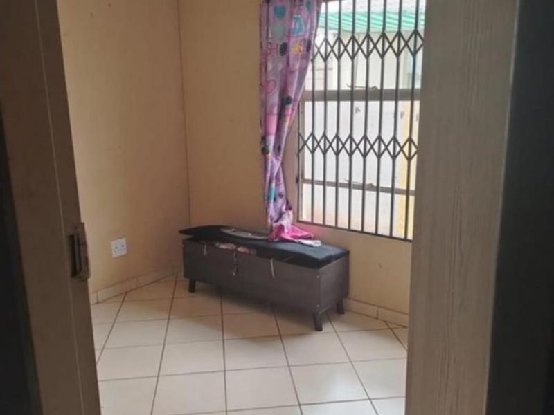 A compact bedroom featuring tiled flooring and a window fitted with a security gate, offering a blank canvas for potential updates.