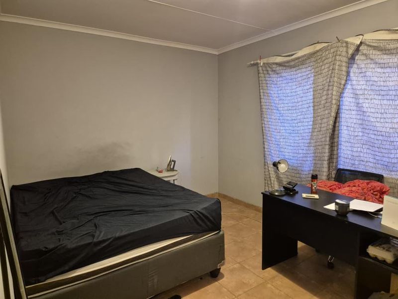 A bedroom featuring tiled flooring and neutral wall finishes, offering a functional space ready for personalization and cosmetic updates.