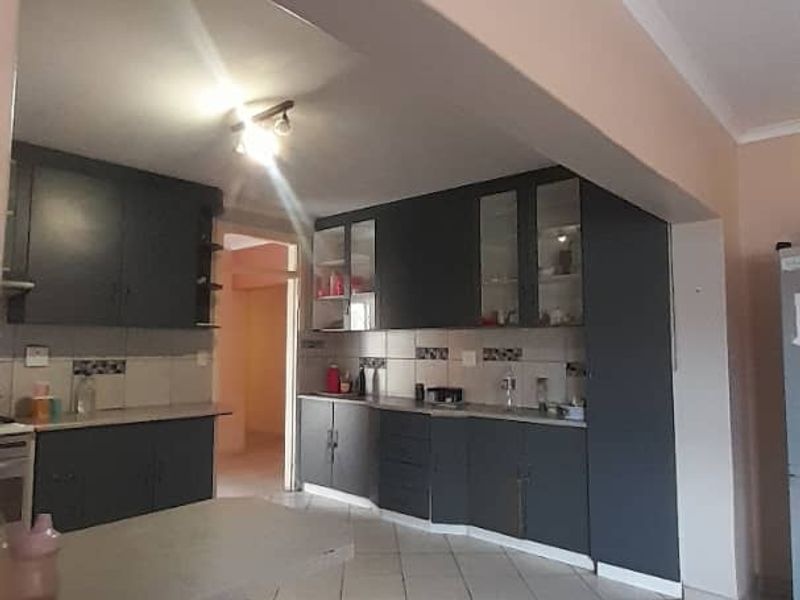 A functional kitchen featuring dark cabinetry, tiled flooring, and a breakfast counter, offering a practical layout with potential for modern updates.
