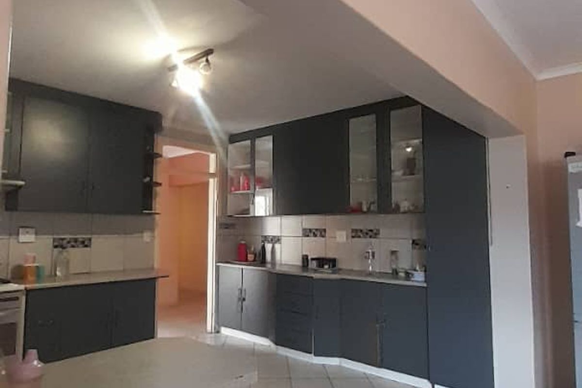 A functional kitchen featuring dark cabinetry, tiled flooring, and a breakfast counter, offering a practical layout with potential for modern updates.