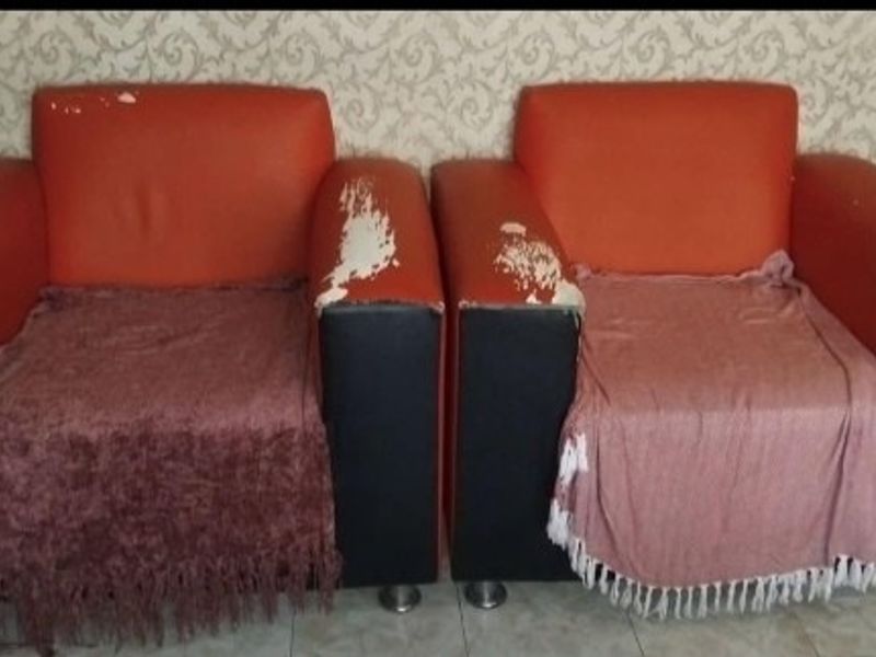 A close-up view of two armchairs placed against a patterned wallpapered wall.