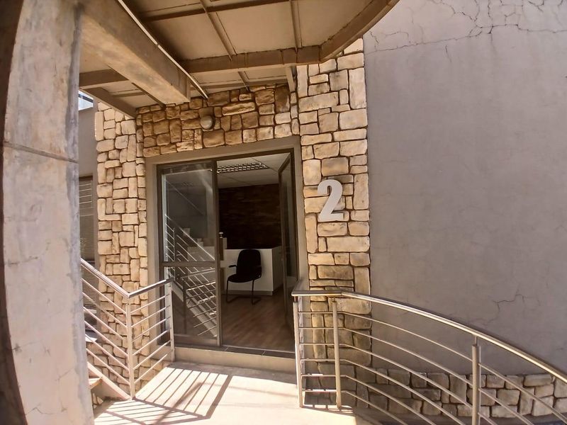 Entrance to office unit 2 featuring stone cladding, a covered walkway, and stainless steel railings.