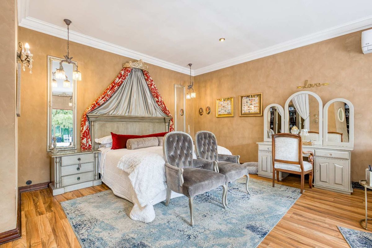 Spacious bedroom featuring warm-toned textured walls, laminate flooring, crown molding, and integrated wall-mounted air conditioning.