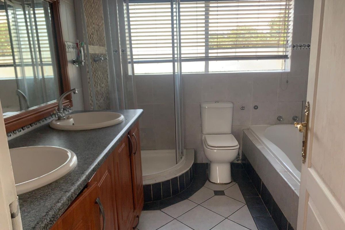A functional bathroom featuring a double vanity, separate shower enclosure, bathtub, and tiled flooring with neutral wall finishes.