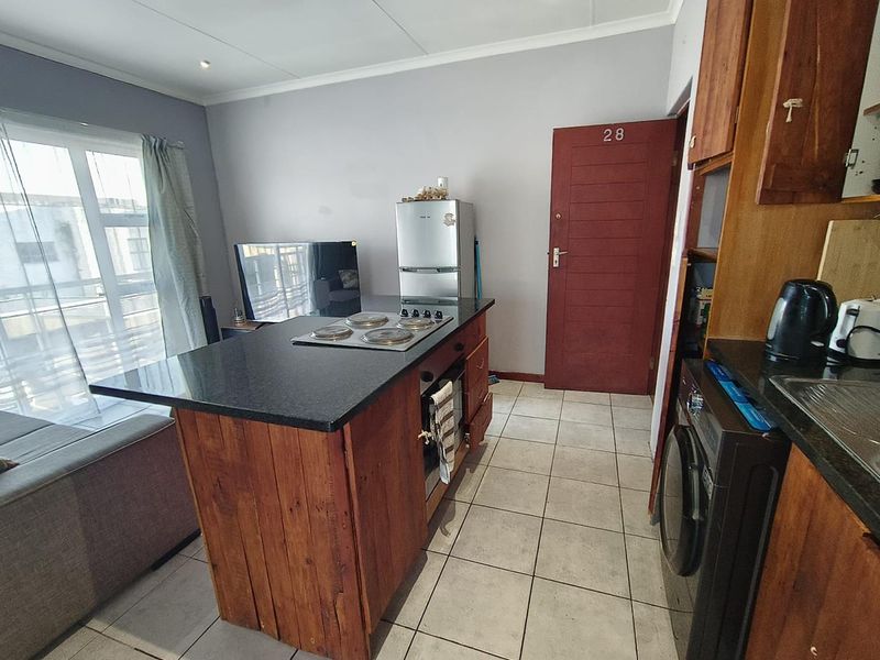 Open plan kitchen area featuring a central island with built-in hob and oven, granite countertops, and tiled flooring, integrated with the living space.