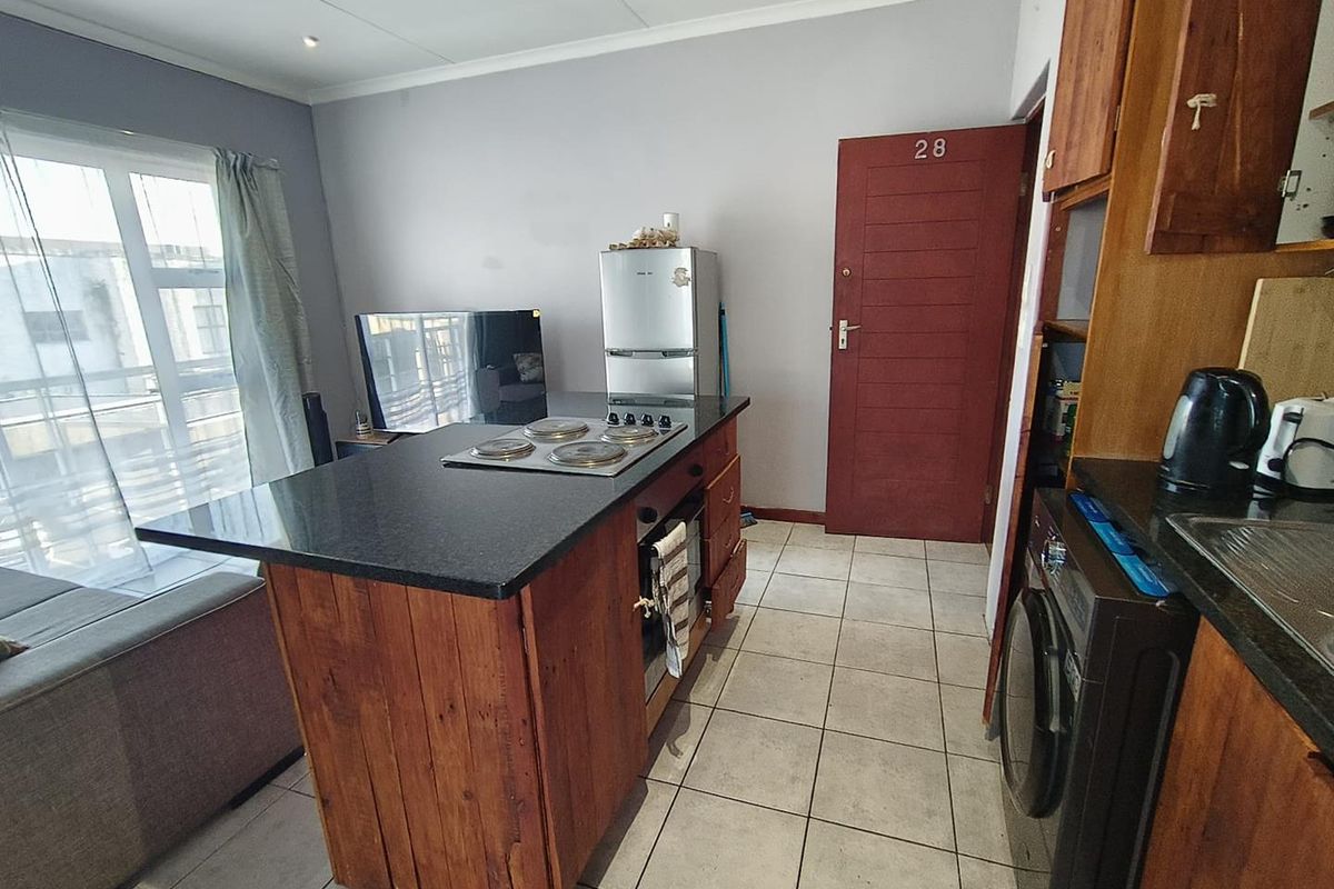 Open plan kitchen area featuring a central island with built-in hob and oven, granite countertops, and tiled flooring, integrated with the living space.