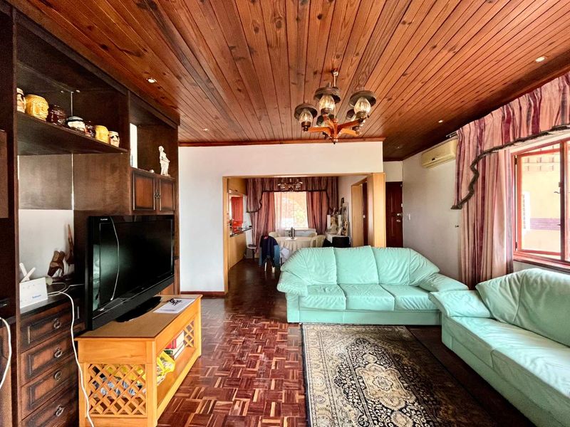 Open-plan living area featuring traditional parquet flooring and a timber-clad ceiling, providing a warm, dated aesthetic with potential for modern renovation.