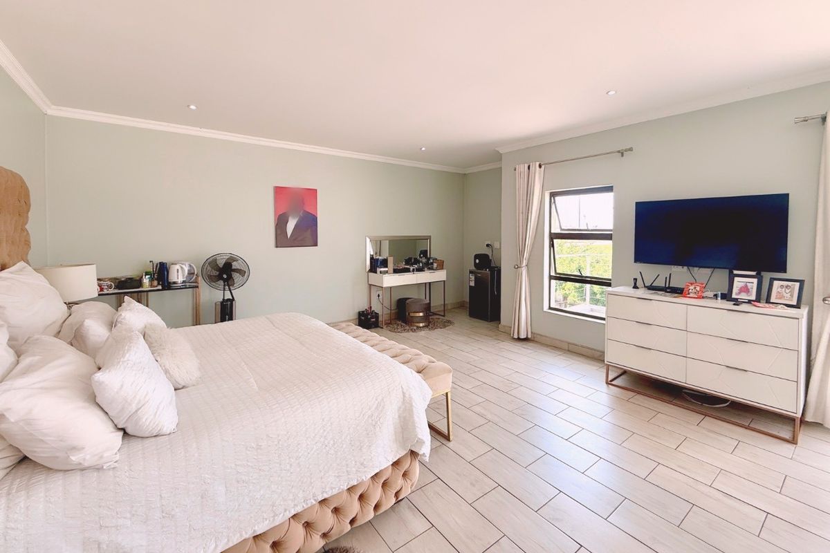 Spacious bedroom featuring light-toned tiled flooring, recessed downlighting, and a large window with curtain fixtures, creating a bright and comfortable living space.