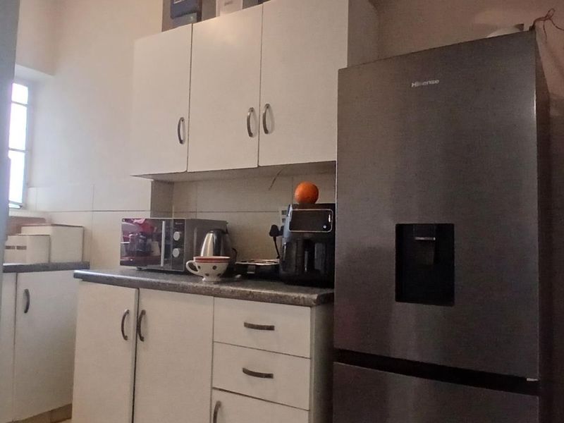 A functional kitchen area featuring white built-in cabinetry, laminate countertops, and tiled backsplash, providing essential storage and workspace.