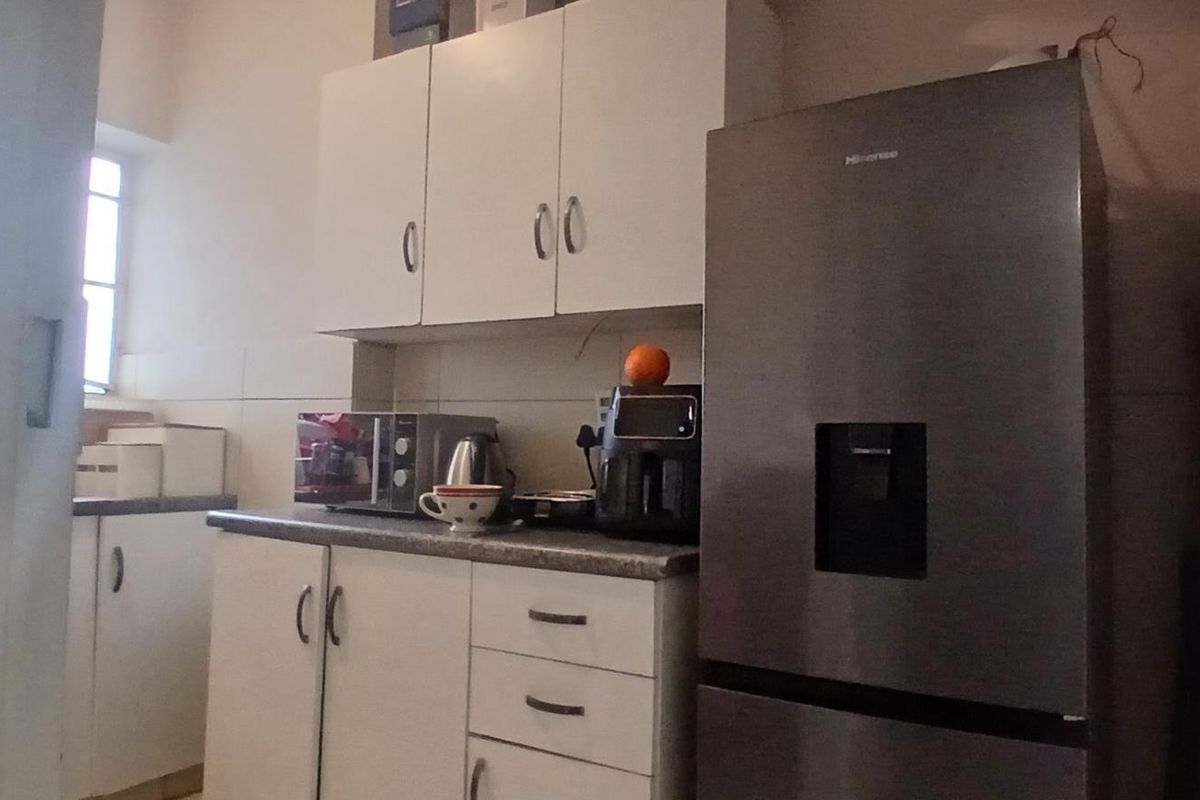 A functional kitchen area featuring white built-in cabinetry, laminate countertops, and tiled backsplash, providing essential storage and workspace.