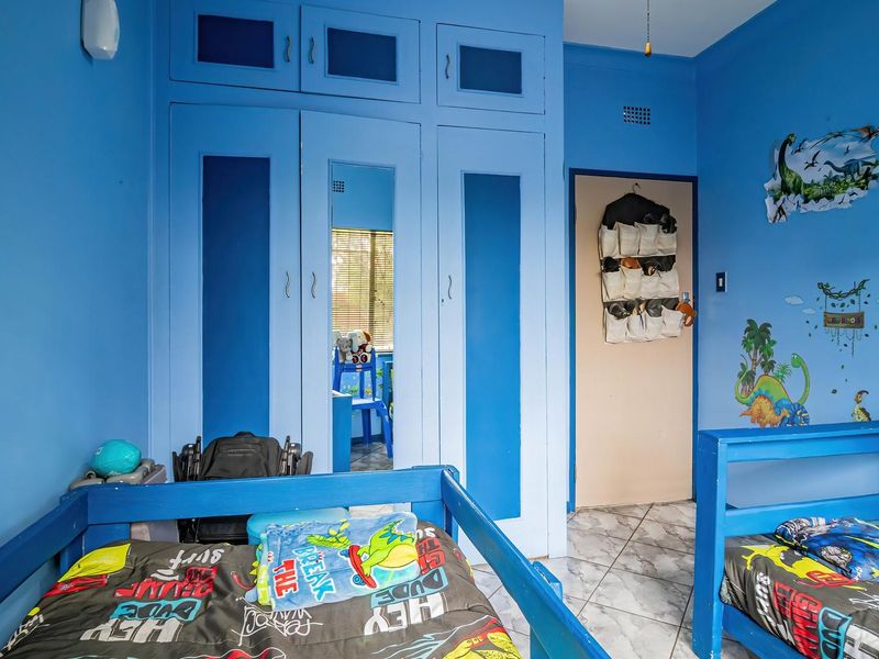 A bedroom featuring built-in cupboards with integrated mirror panels and tiled flooring.