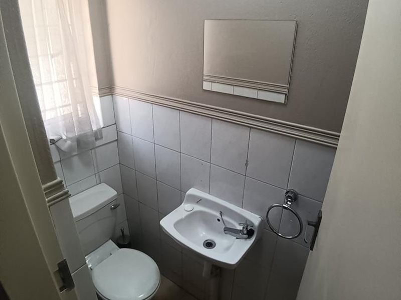 A compact guest bathroom featuring a wall-mounted basin, toilet, and neutral tiled finishes.