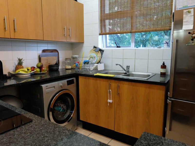 A functional kitchen featuring laminate cabinetry, granite countertops, a stainless steel double sink, and integrated plumbing for a washing machine.