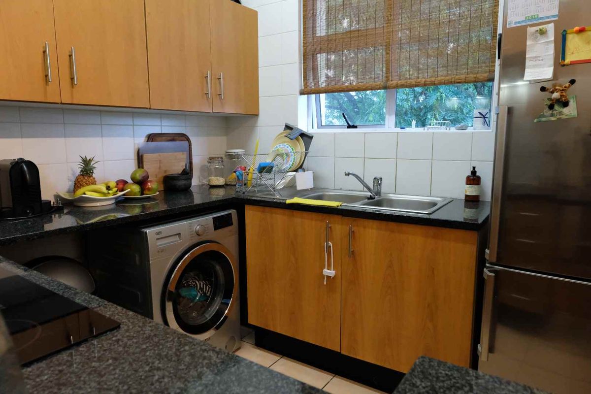 A functional kitchen featuring laminate cabinetry, granite countertops, a stainless steel double sink, and integrated plumbing for a washing machine.