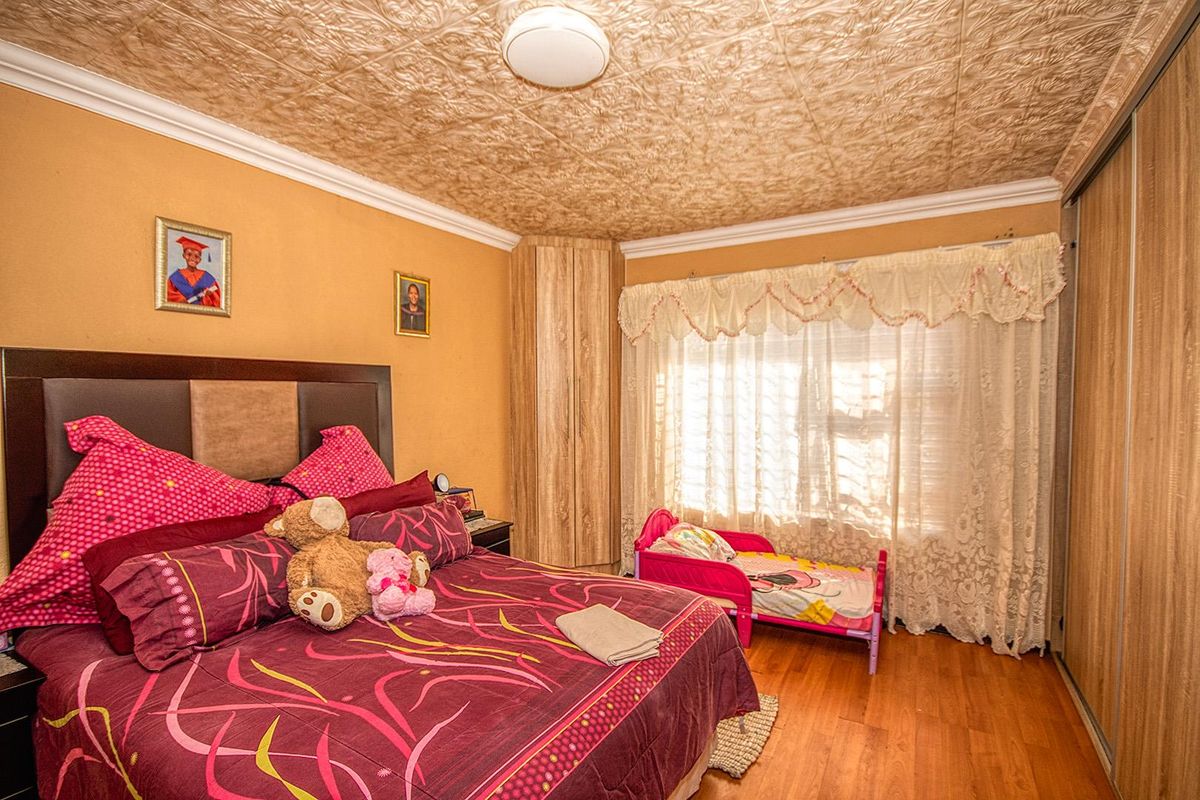A bedroom featuring built-in wooden cupboards, laminate flooring, and a textured ceiling finish.