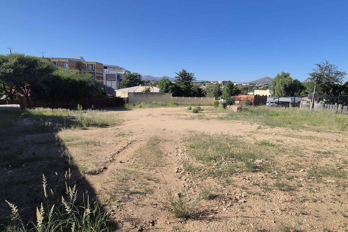 A vacant residential plot featuring open ground, boundary walls, and perimeter fencing, offering a clear space for future development.